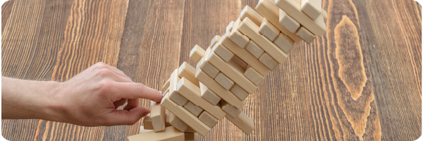 wooden A hand knocking a wooden Jenga tower over