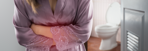 woman in dressing gown clutching her stomach denoting pain with a toilet in the background.