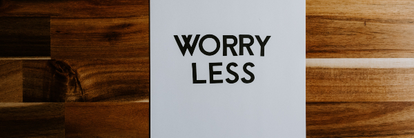 Black letters spell out 'worry less' on a white piece of paper.