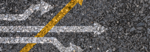 White arrows pointing in the same direction to the right painted onto a road and a yellow arrow pointing in diagonally across them to represent disruption to go with our article about factors that can affect the gut microbiome