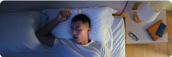 A young man lying in bad asleep with his mouth open mouth breathing during the night. 