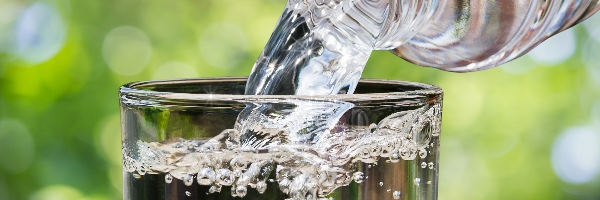 Close-up of clear water being poured from a bottle into a glass.