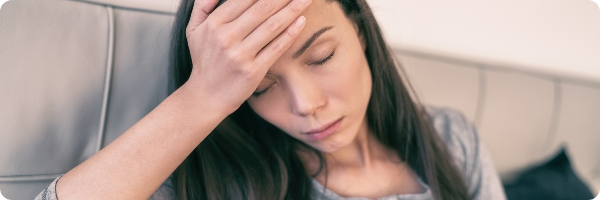 Women with a headache holding her head after a night out drinking.