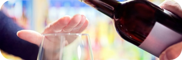 Man stopping wine being poured into a glass to overcome alcohol addiction.