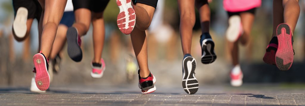 Group of runners mid stride moving away.
