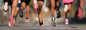 Group of runners mid stride moving away.
