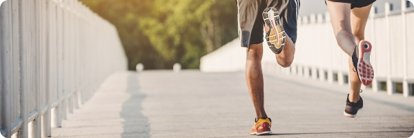 Two people running across a bridge, heading away.