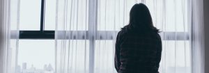 Depression and anxiety silhouette of a woman with her back to the camera looking out of the window.