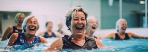 A group of smiling and laughing older ans middle-aged women in a swimming pool doing an aqua fit class as an example of how one can improve their cardiovascular endurance.