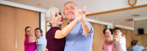 Happy middle aged Caucasian couple at a dance class, with other couples in the background.