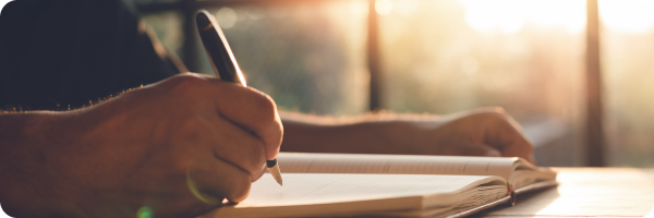 A man writing in a notebook to represent identifying nicotine craving triggers
