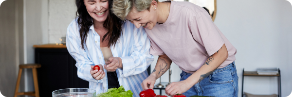 Two women laughing as the cut vegetables together.