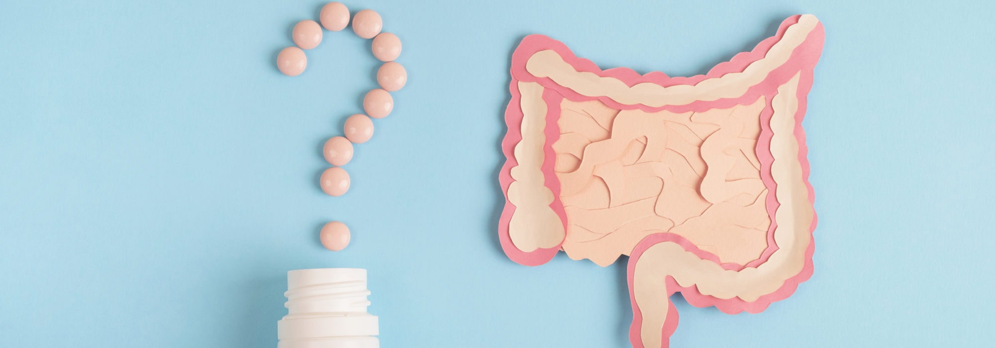 Small round pink pills in the shape of a question mark over a white plain pill bottle next to an image representation of the intestines and gut all to represent the topics of IBS, the gut microbiome and antibiotic use. Both on a pale blue background.