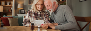 Older couple reading a medication leaflet and packet to check medication interactions