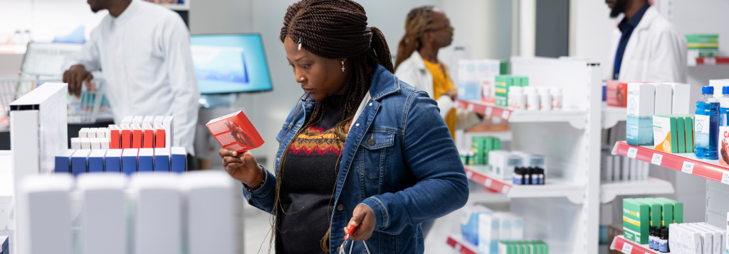 A middle-aged black woman looking at a medication box in a pharmacy to represent how to take over the counter medicines safely.